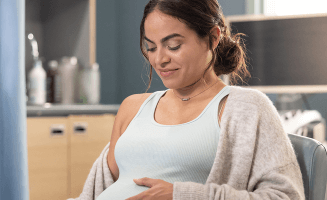 Actor portrayal of a pregnant woman feeling her belly