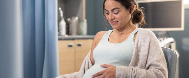Actor portrayal of a pregnant woman feeling her belly