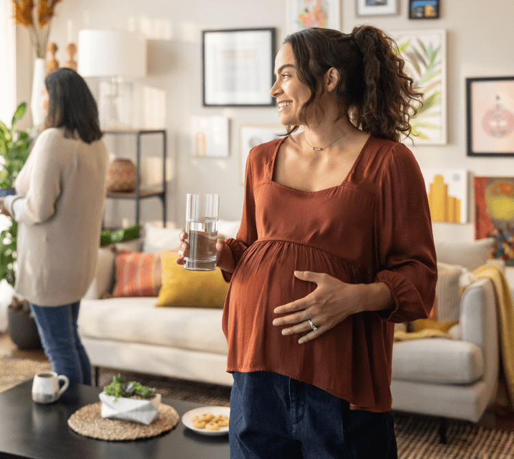 Pregnant woman smiling holding her stomach